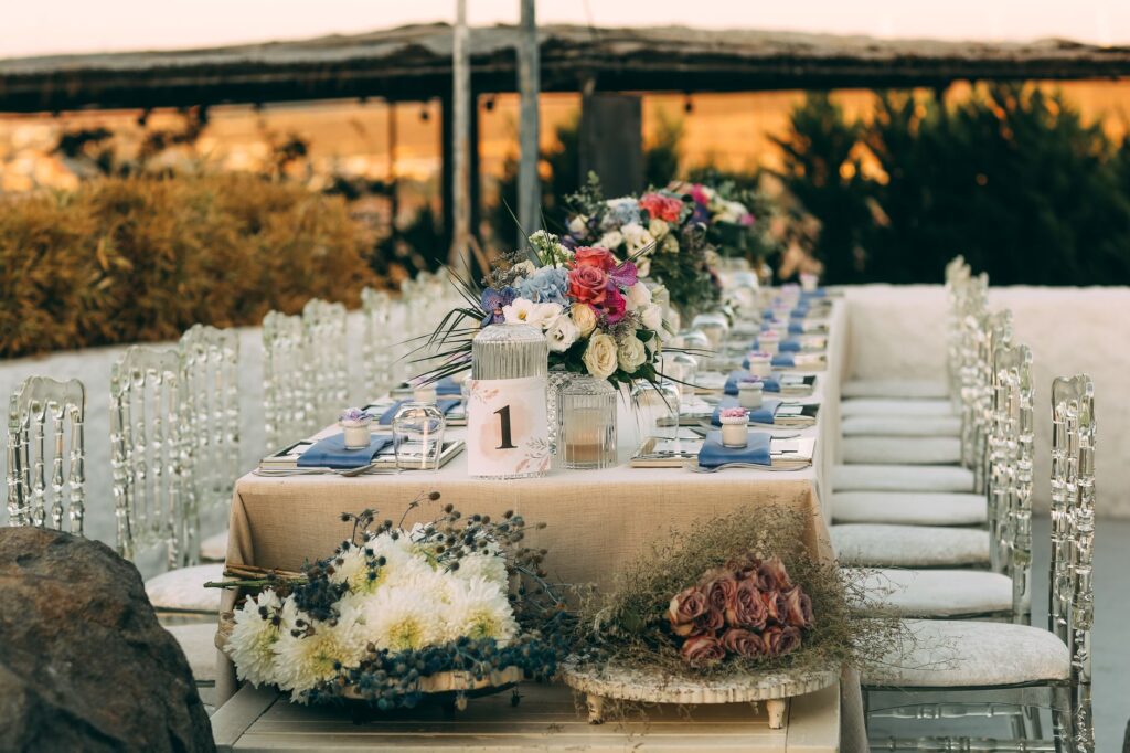 Elegant outdoor wedding reception table set with floral centrepieces, candles, and fine tableware at golden hour