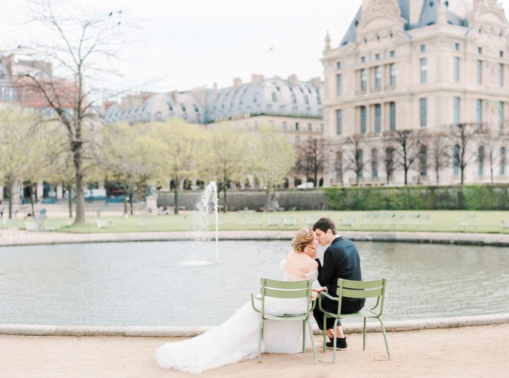 Newlywed couple sitting by a fountain in the Tuileries Garden, Paris — an example of an outdoor Paris wedding venue setting