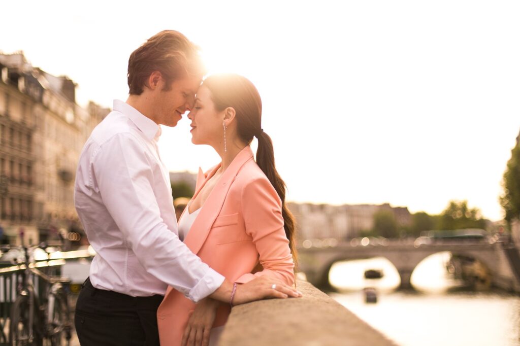 Romantic couple embracing on a bridge over the Seine River at golden hour in Paris