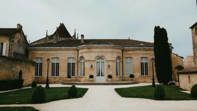 Honey-hued French château stone facade with formal grounds and cypress trees, representing a Provence wedding venue similar to Château de Sannes