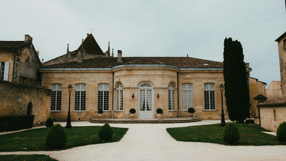 Honey-hued French château stone facade with formal grounds and cypress trees, representing a Provence wedding venue similar to Château de Sannes