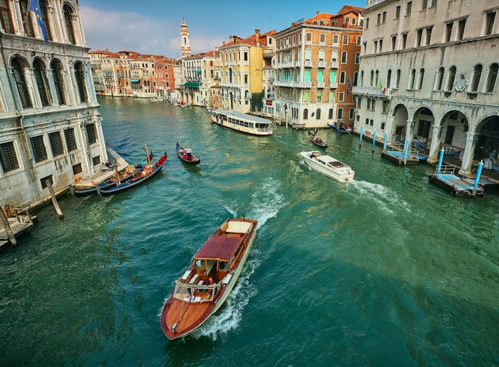Elegant wooden water taxis and vaporettos navigating the Grand Canal past ornate Venetian palazzo facades