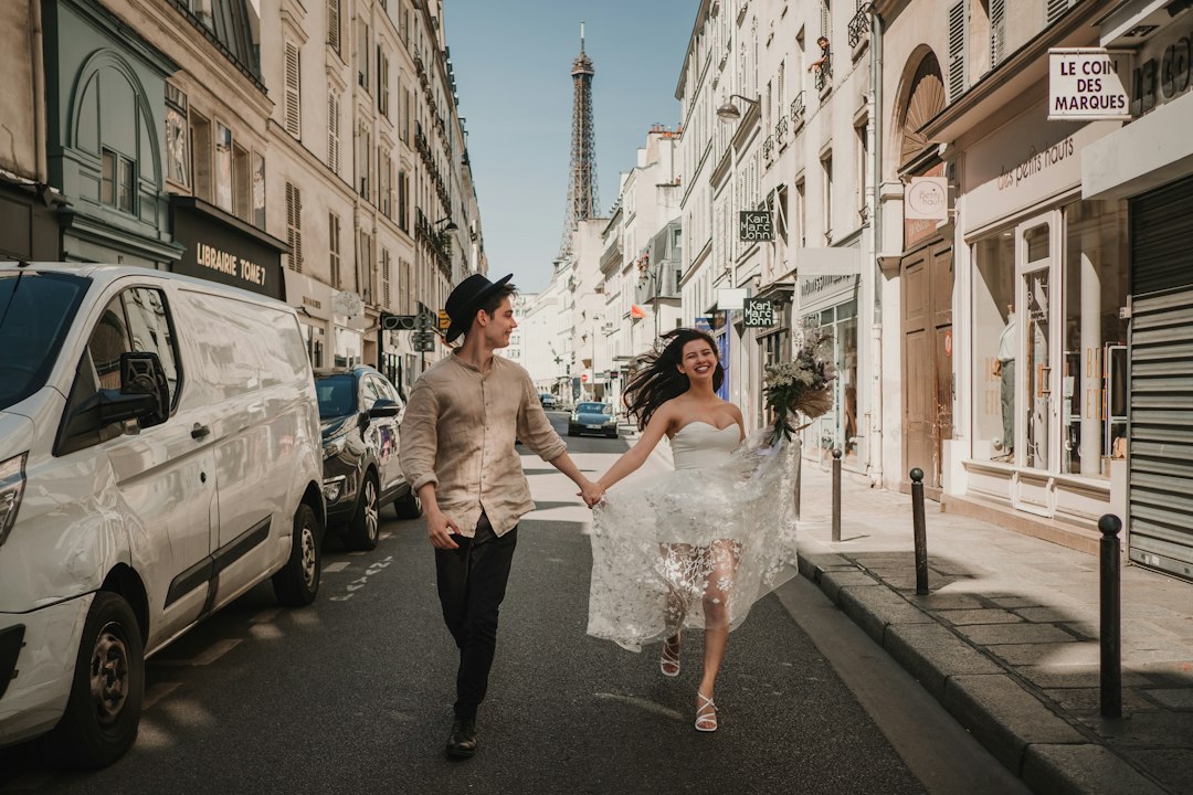 Bride and groom running joyfully through a Paris street with the Eiffel Tower in the background