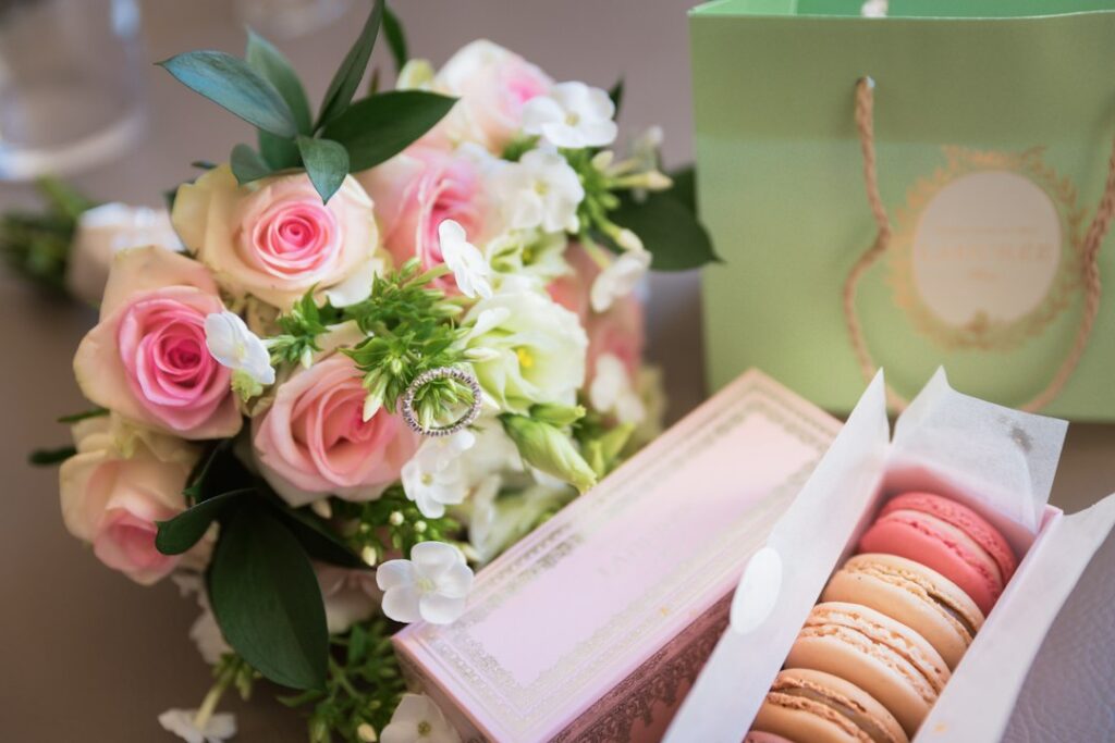 Pink roses, a wedding band, and French macarons on a table — elegant French wedding details