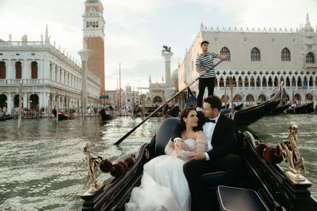A wedding couple sitting in a gondola on the Grand Canal in Venice with St. Mark's Square in the background