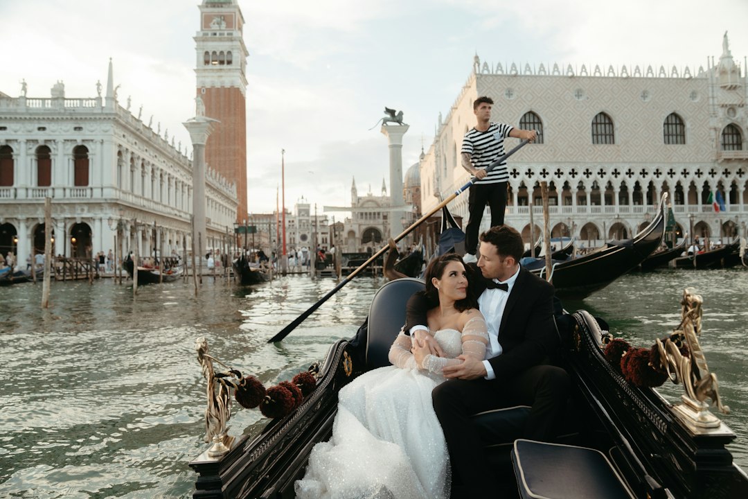 A wedding couple sitting in a gondola on the Grand Canal in Venice with St. Mark's Square in the background