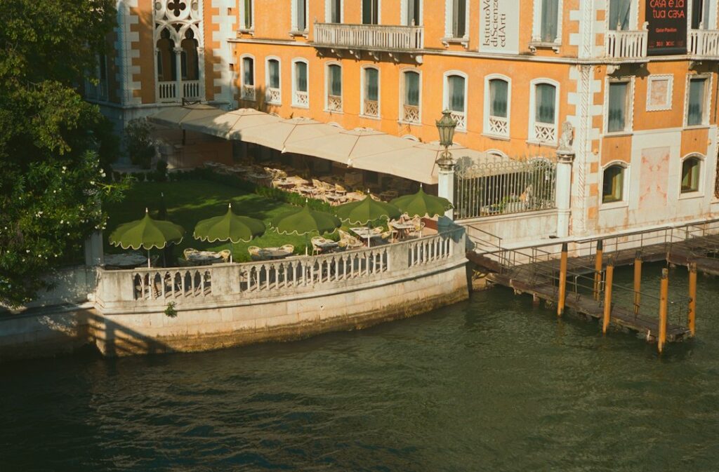 Luxury Venetian palazzo terrace with garden seating and outdoor umbrellas on the Grand Canal at golden hour