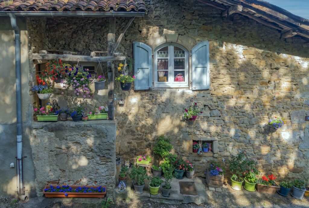 Rustic honey-stone French farmhouse with blue shutters and flower pots — typical Dordogne countryside wedding venue