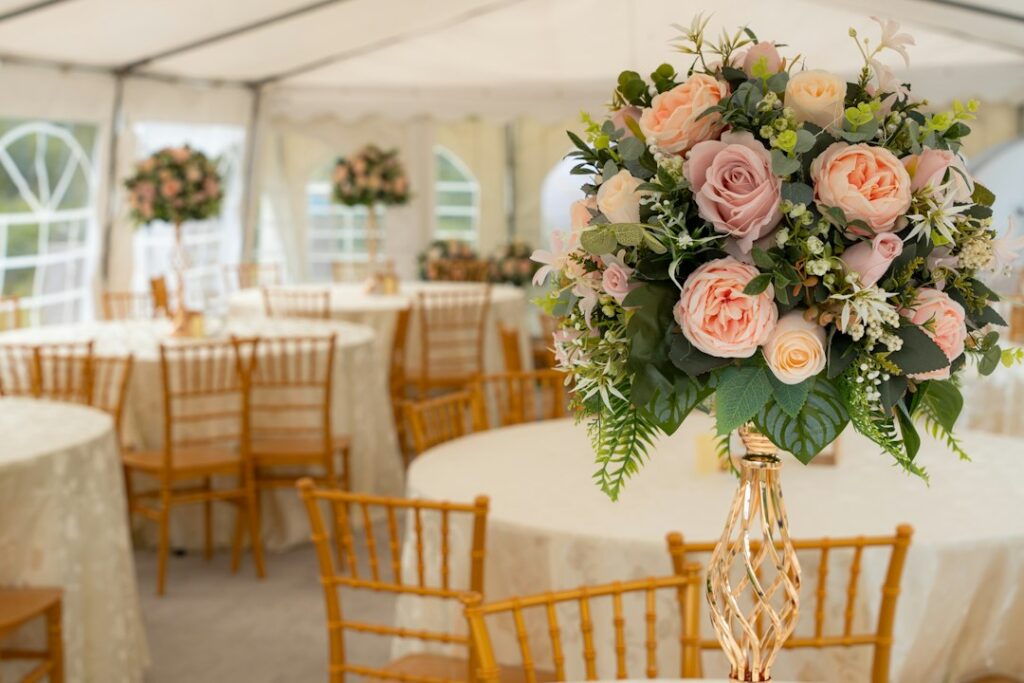 Blush wedding venue with tall floral centrepieces of pink and peach roses set on round tables with Chiavari chairs